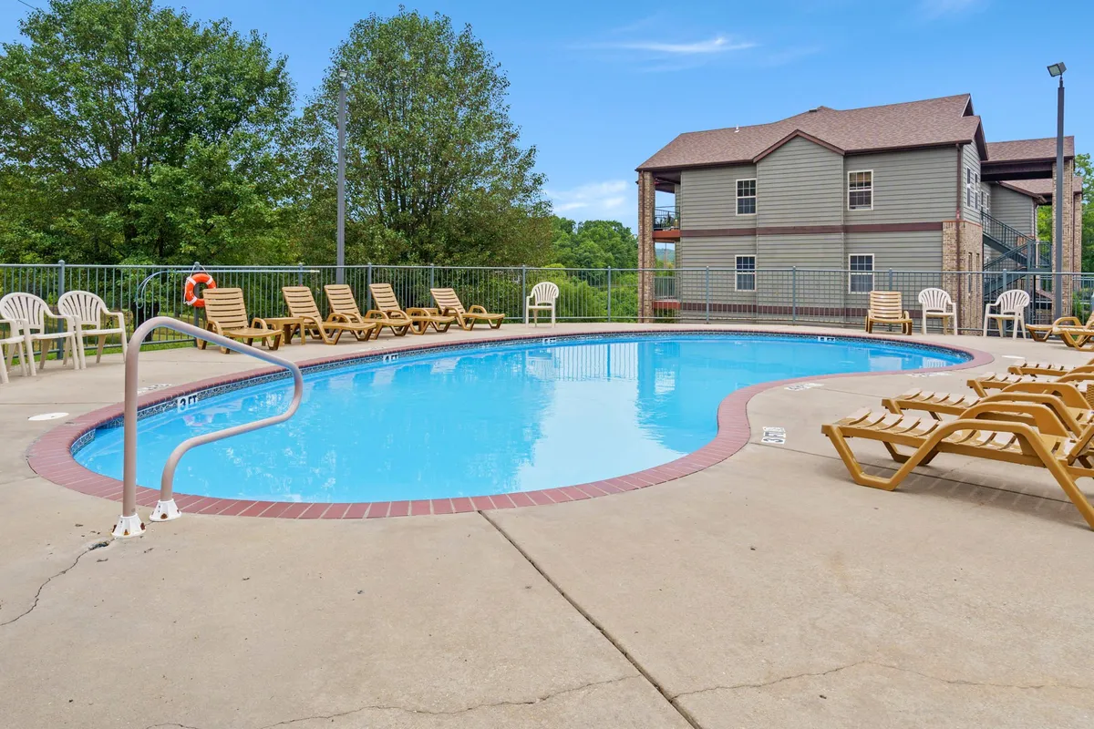 A sparkling outdoor swimming pool is surrounded by comfortable lounge chairs and lush greenery, exuding a leisurely and inviting atmosphere. The blue water and ample seating emphasize opportunities for sunbathing, socializing, and unwinding.