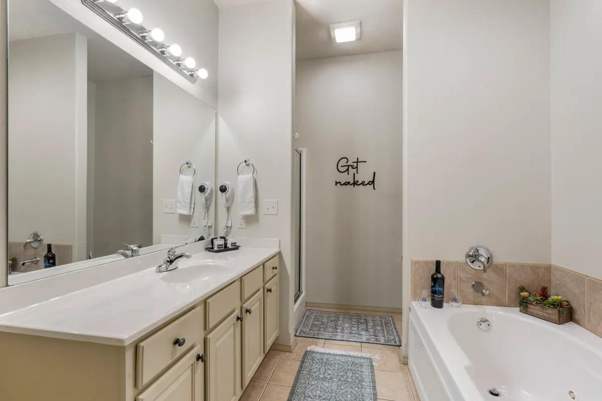 A spacious ensuite bathroom featuring a freestanding jetted tub, double sinks in a large vanity, and decorative touches. The atmosphere blends calm with a playful touch, ideal for relaxing self-care routines.