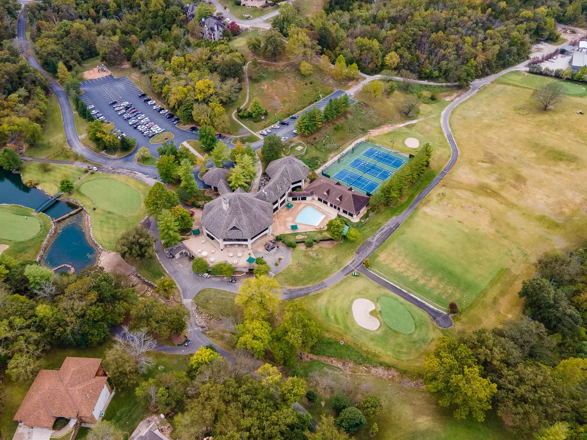 A vibrant aerial shot showcases the heart of the resort community, capturing the swimming pool, tennis courts, the championship golf course, and the welcoming clubhouse. Lush greenery and well-maintained grounds create a sense of leisure and upscale amenities.