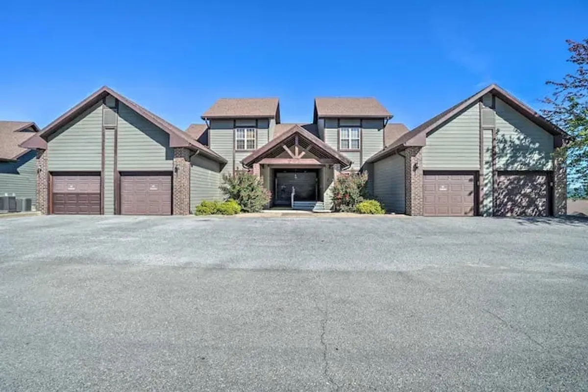 The main entrance of a home with well-maintained landscaping, inviting garage doors, and a welcoming porch, providing a sense of arrival and privacy within a gated community.